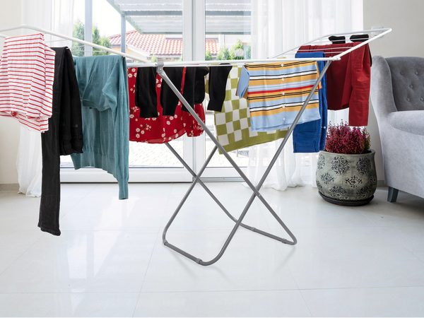 ABN Finest winged clothes airer holding a full load of washing, indoors in a bright living room and outdoors on a garden lawn